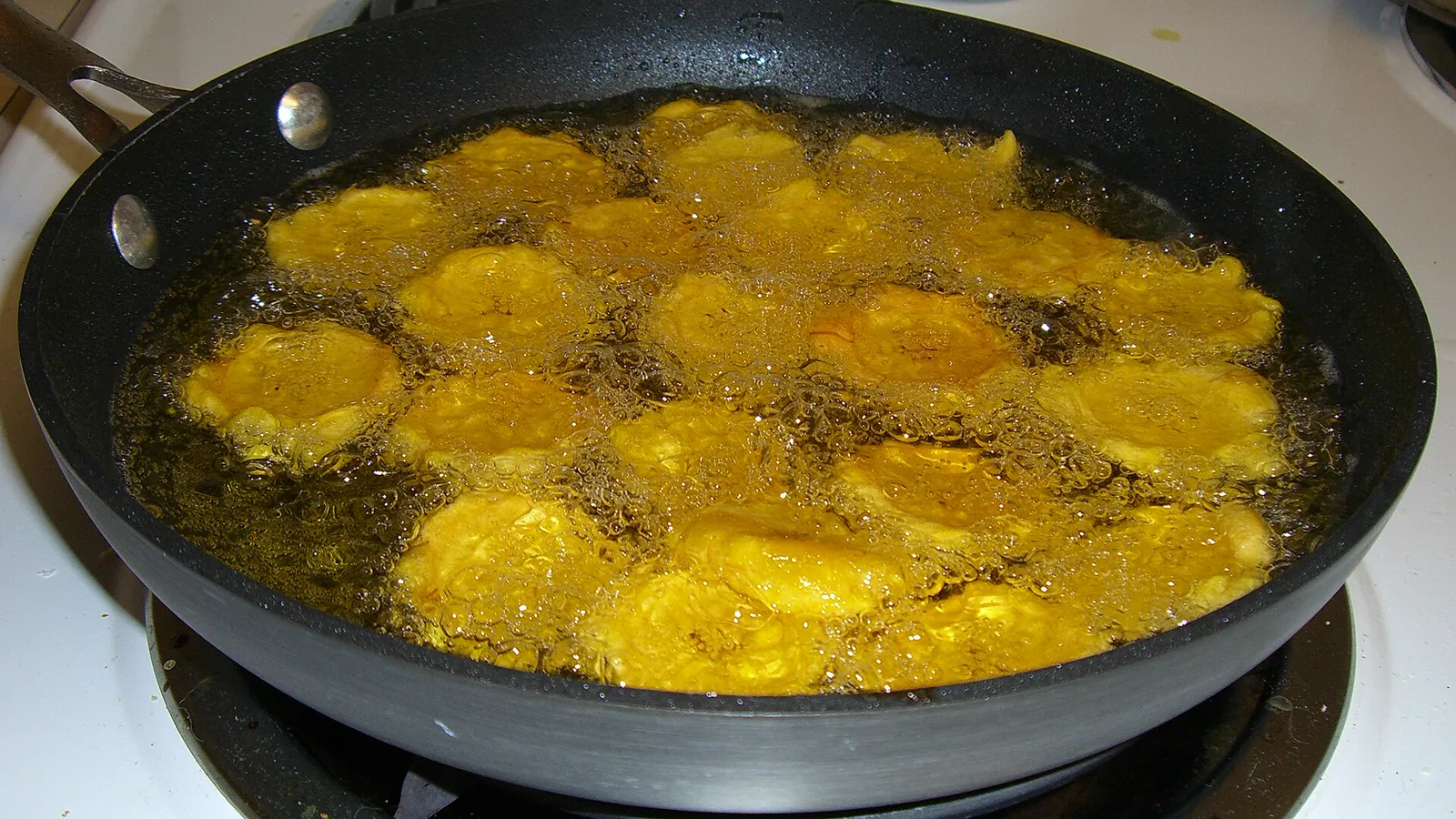 Slices of plantain frying in a pan