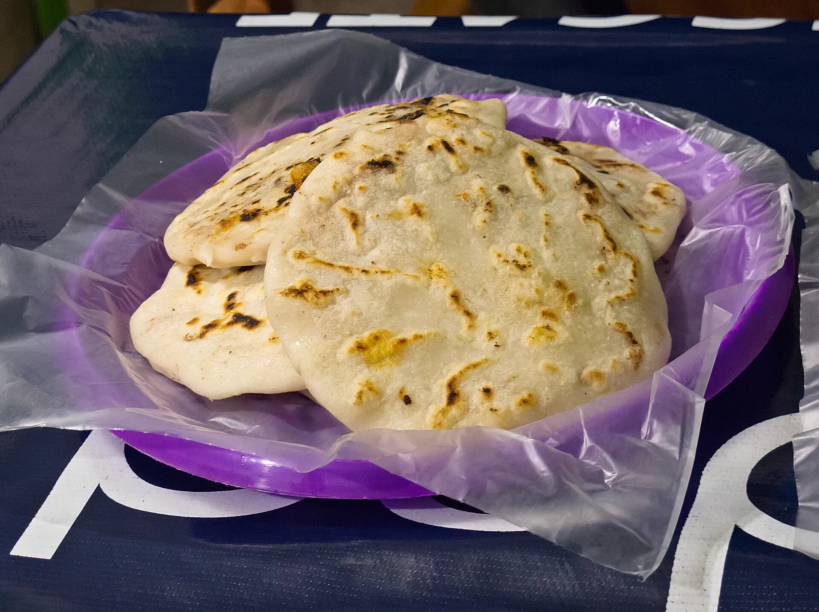 Three golden pupusas on a purple plate
