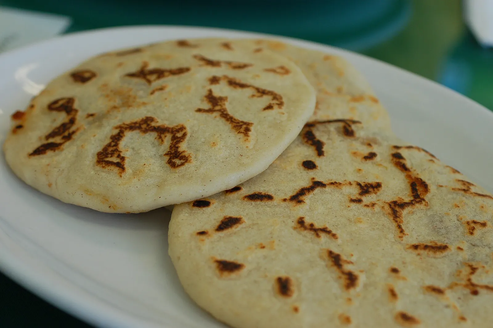 Two plain pupusas revueltas on a white plate